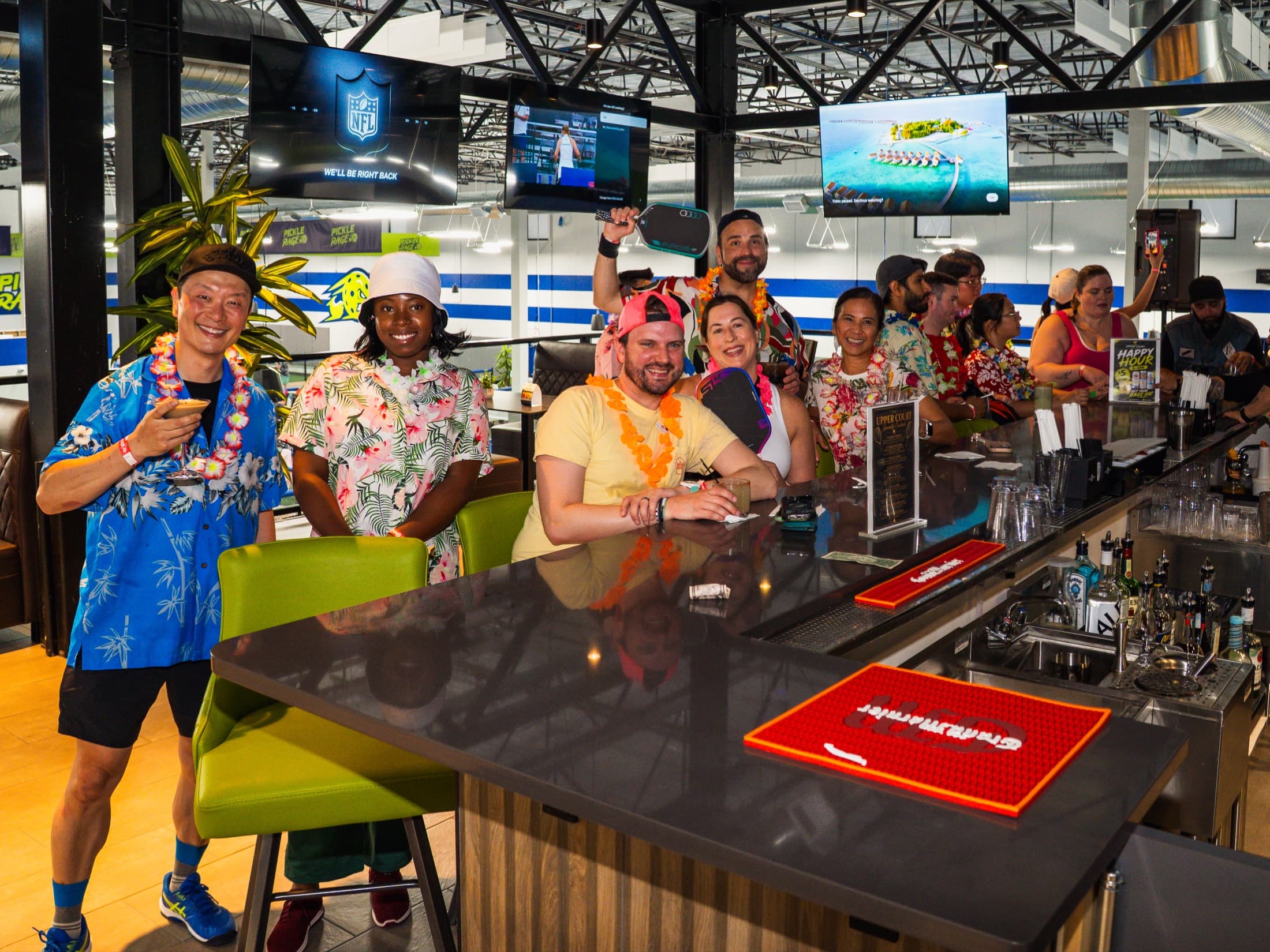 Birthday party guests gathering at The Upper Court bar with indoor pickleball courts behind them